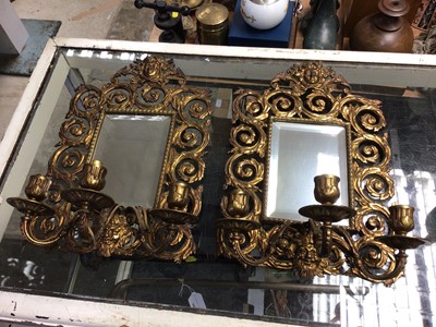 Lot 240 - Pair of heavy brass three-branch mirror candelabra, decorated with masks and scrollwork motif, 40 x 26cm