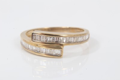 Lot 119 - Diamond crossover ring with channel set baguette cut diamonds in 9ct yellow gold setting