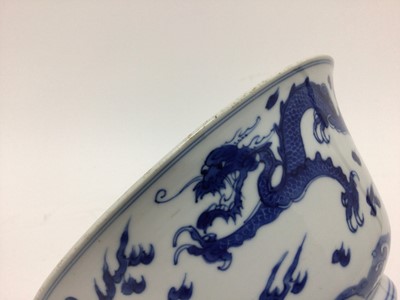 Lot 129 - Fine Chinese blue and white bowl, Kangxi period, of round form with straight foot and flared rim, decorated with dragons chasing flaming pearls, amongst stylised clouds and waves, prunus flowers on...