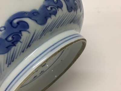 Lot 129 - Fine Chinese blue and white bowl, Kangxi period, of round form with straight foot and flared rim, decorated with dragons chasing flaming pearls, amongst stylised clouds and waves, prunus flowers on...