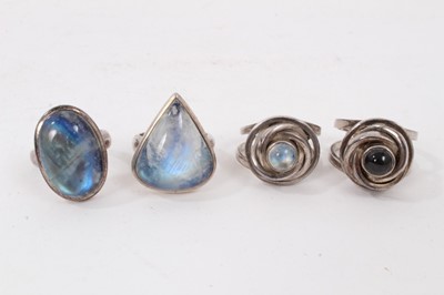 Lot 230 - Two silver abstract design rings, one set with a rainbow moonstone cabochon and one with black star diopside cabochon, together with two other silver large rainbow moonstone rings (4)