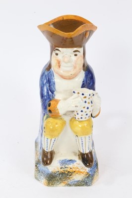 Lot 10 - Prattware Toby jug, circa 1800, seated and holding frothing jug of beer, decorated in typical colours, with sponged base, back and handle