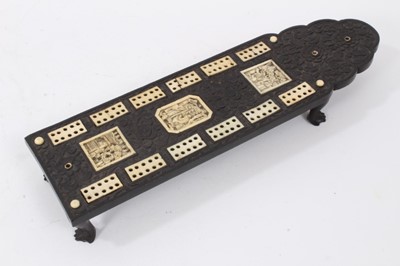 Lot 225 - 19th century Chinese black hardwood cribbage board, with carved floral decoration, inlaid ivory markers and carved plaques with Chinese scenes, slide covered peg box with four pegs, on four carved...