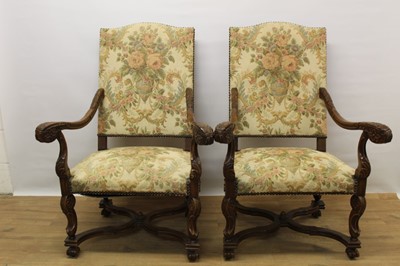 Lot 1387 - Pair of Carolean style carved walnut open armchairs, with arched pad back and seat and scrolled arms, raised on cabriole legs united by wavy stretchers
