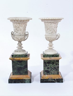 Lot 1 - Fine pair of ivory campana vases, circa early 19th century and probably Italian, carved in relief with Bacchanalian scenes, with satyr mask handles, on square marble pedestal bases, 19.5cm high