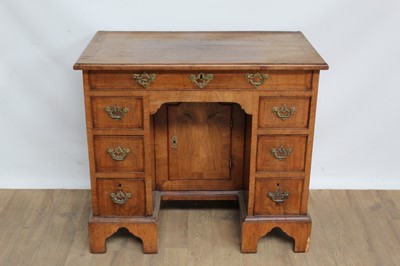 Lot 1335 - 18th century walnut kneehole desk with an arrangement of seven drawers and central sliding cupboard, on bracket feet