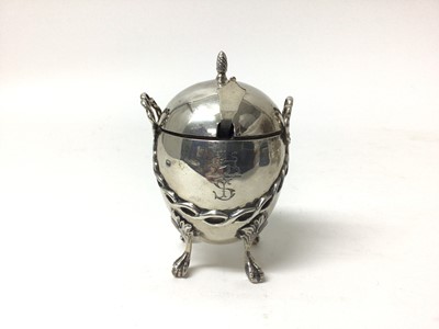 Lot 221 - Victorian silver mustard, liner and associated spoon, London 1862, of egg form with swag decoration and four paw-and-ball-feet, engraved crest to front, 9cm high