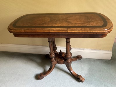 Lot 1231 - Victorian figured walnut and ebonised banded card table, of rounded rectangular form on fluted columns and splayed quadruped supports on castors, 98cm wide x 49 cm deep x 75cm high