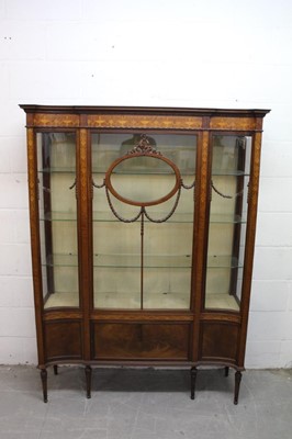 Lot 1303 - Good quality early 20th century mahogany and inlaid display cabinet, of shallow concave outline, with carved stepped cornice and glass shelves enclosed by swag carved astragal glazed door, enclosed...