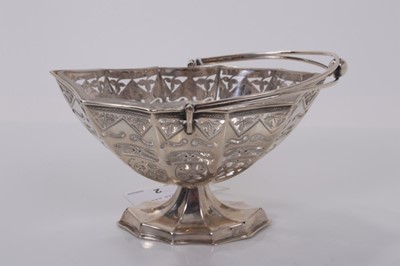 Lot 2 - Edwardian silver sugar basket of navette form with pierced and engraved decoration, swing handle and clear glass liner, raised on pedestal foot, (Birmingham 1901), maker William Aitken, 15cm wide,...