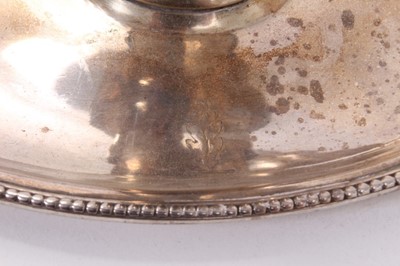 Lot 414 - George III silver chamberstick of oval form with beaded borders, removable snuffer and sconce, and engraved armorials, (London 1786), maker Thomas Chawner, all at 8ozs, 16cm in diameter.