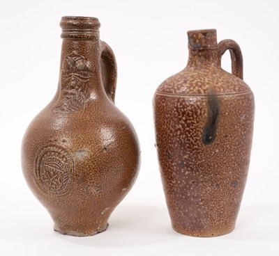 Lot 10 - A 17th century German stoneware Bellarmine jug, decorated with a mask and coat of arms, 23cm high
