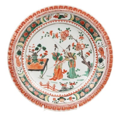 Lot 16 - A Chinese famille verte plate, Kangxi period, decorated with two courtesans in a garden, pie crust rim, 24cm diameter