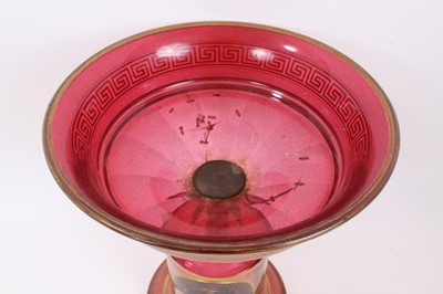 Lot 152 - A late 19th century Bohemian cranberry glass centrepiece, the circular bowl with gilt Greek Key pattern, above a pedestal base with gilt patterns and oval painted portrait of a young woman, 33.5cm...