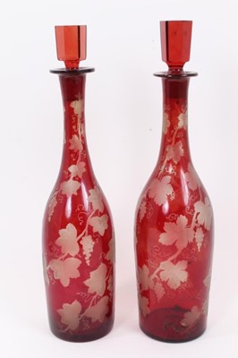 Lot 199 - A pair of Edwardian cranberry glass decanters with etched vine leaf decoration, 35.5cm high