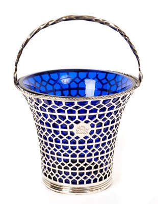 Lot 423 - George III silver swing handled sugar basket of flared cylindrical form, with engraved armorial and pierced diaper decoration, fitted blue glass liner (London 1769) Edward Aldridge II. All at appro...