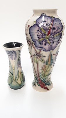 Lot 1135 - Moorcroft pottery vase decorated with purple flowers on cream and green ground, dated 2002, 12.5cm high, together with another decorated with purple flowers, signed and dated 2001, 20.5cm high  (2)