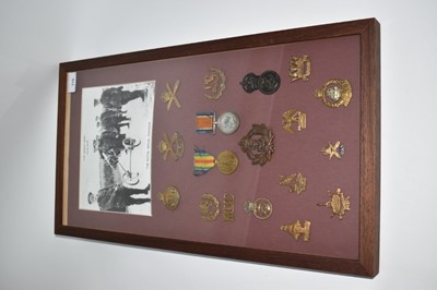 Lot 715 - First World War pair comprising War and Victory medals named to 10743 PTE. E. Jenkins. M.G.C., mounted in a glazed frame with a selection of First World War cap badges.