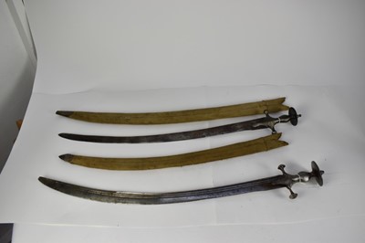 Lot 951 - Two 19th century Indian Tulwar swords with steel disc hilts, curved blades with associated scabbards (2)