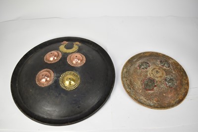Lot 954 - 19th century Indian black lacquered shield with copper and brass crescent and boss decoration and remnants of handles 44 cm and another parrying shield with decorative bosses 29 cm (2)