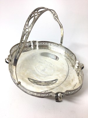 Lot 331 - George V silver cake basket with pierced border and central swing handle, raised on four scroll feet. The centre of the basket with presentation inscription.