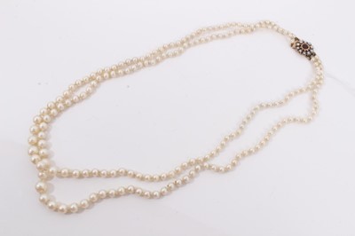 Lot 375 - Cultured pearl two strand necklace with 9ct gold flower head clasp set with a garnet surrounded by seed pearls