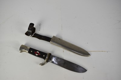 Lot 988 - Nazi Hitler Youth knife / dagger with chequered plastic grip, set with enamel swastika badge, plated mounts, etched blade marked RZM M7/51 39 in plated painted scabbard with integral frog