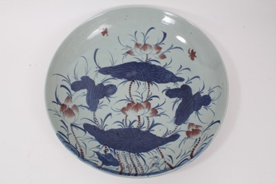 Lot 19 - A 19th century Chinese porcelain charger, painted in underglaze blue and red with lotus flowers