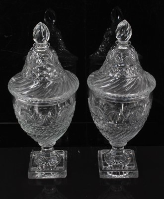 Lot 55 - A pair of Regency cut glass covered urns or bonbonnieres, with bands of fluting, diamond and foliate patterns, on square stepped lemon squeezer bases, 31cm high
