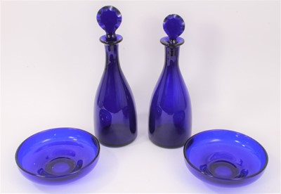 Lot 73 - A near pair of 19th century Bristol blue glass decanters with facet-cut stoppers, the larger measuring 32cm high, together with a near pair of Bristol blue finger bowls (4)