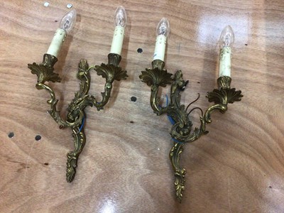 Lot 59 - A pair of gilt metal two-branch wall lights of scrolling acanthus form, 45cm high including bulbs