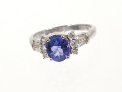 Lot 454 - Tanzanite and diamond ring with an oval mixed cut tanzanite flanked by six round brilliant cut diamonds and tapered baguette cut diamond shoulders on 18ct white gold shank.