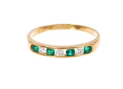 Lot 435 - Emerald and diamond eternity ring with three brilliant cut diamonds interspaced by four round mixed cut emeralds in 18ct yellow gold channel setting.