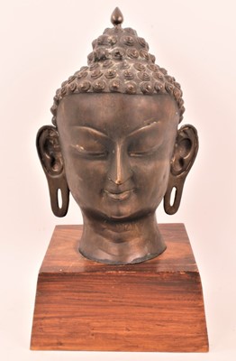 Lot 799 - Large Tibetan bronze head of buddha on a wooden base