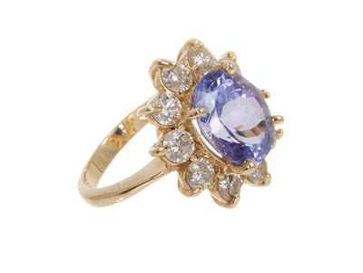 Lot 438 - Tanzanite and diamond cluster ring with an oval mixed cut tanzanite measuring approximately 10.8mm x 8.8mm x 6.2mm surrounded by a border of ten brilliant cut diamonds in gold claw setting on 14ct...