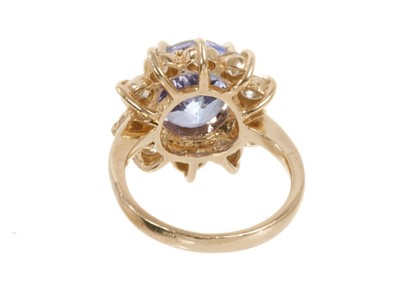 Lot 438 - Tanzanite and diamond cluster ring with an oval mixed cut tanzanite measuring approximately 10.8mm x 8.8mm x 6.2mm surrounded by a border of ten brilliant cut diamonds in gold claw setting on 14ct...