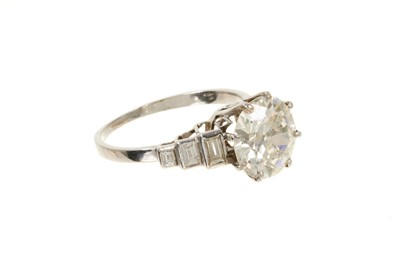 Lot 632 - Art Deco diamond single stone ring with a round old European cut diamond estimated to weigh approximately 2.5cts in eight claw setting flanked by six baguette cut diamonds to the stepped shoulders...