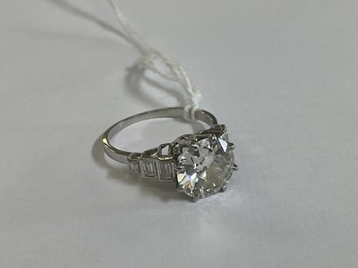 Lot 632 - Art Deco diamond single stone ring with a round old European cut diamond estimated to weigh approximately 2.5cts in eight claw setting flanked by six baguette cut diamonds to the stepped shoulders...