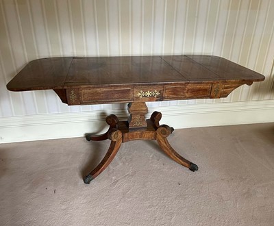 Lot 1051 - William IV rosewood and brass inlaid sofa table, with rounded rectangular drop-leaf top over two drawers to the tablet frieze on platform base and splayed supports on castors, 151cm wide x 66cm dee...