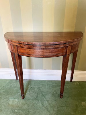 Lot 1077 - George III mahogany and fruitwood crossbanded demi-lune card table, the fold over top enclosing green baize lined interior raised on square tapered gaitered legs, 88cm wide x 47cm deep x 76cm high