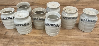 Lot 1411 - Group of eight late 19th/early 20th century white banded pottery kitchen storage jars, with titles printed in black in ribbons, including 'Coffee', 'Barley', 'Currants', etc, 15.5cm high