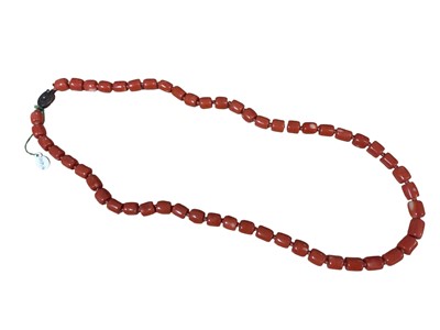 Lot 7 - Old Chinese coral necklace with barrel shaped polished beads and oval silver gilt clasp with wire work flower decoration, 63cm long