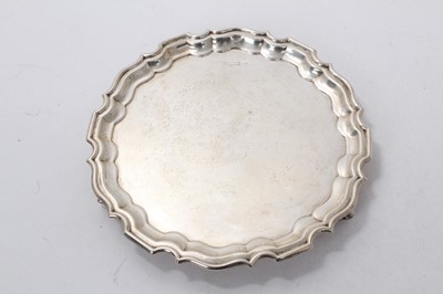 Lot 517 - George V silver salver of circular form, with pie crust border, raised on three scroll feet, (Sheffield 1910), maker Walker & Hall, 10ozs, 21cm in diameter.