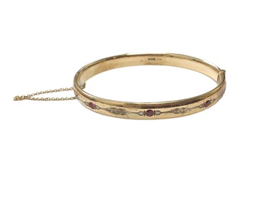 Lot 80 - 9ct gold hinged bangle set with rubies and diamonds