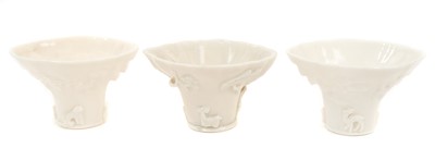 Lot 55 - Three Chinese blanc-de-chine libation cups, probably 17th century, each decorated in relief with a deer, crane, tiger and dragon, 6cm high
