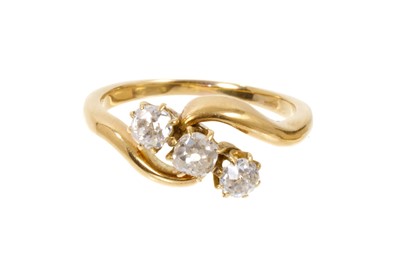 Lot 557 - Diamond three stone ring in 18ct gold cross-over setting