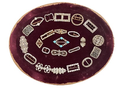Lot 2080 - A group of paste and enamel buckles and clips mounted on velvet and in oval glazed frame.