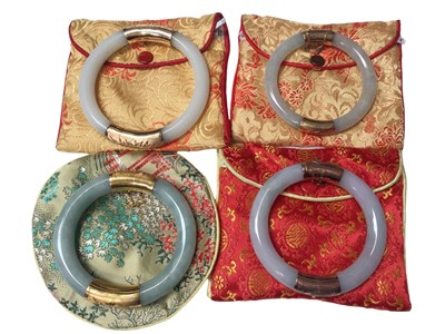 Lot 166 - Four Chinese jade/ green hard stone polished bangles with 14ct gold and yellow metal mounts