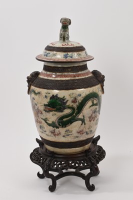 Lot 57 - Chinese famille verte crackle glazed vase and cover, circa 1900, decorated with dragons chasing a flaming pearl, mask handles and foo dog knop, four-character mark to base, with carved wooden stand...