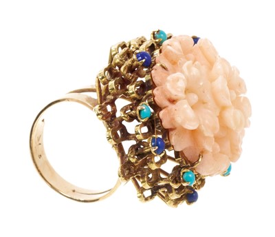 Lot 587 - Large 1960s cocktail ring with a carved pink coral floral cluster in gold abstract setting scattered with lapis lazuli and turquoise cabochons, the cluster measuring approximately 43 x 30mm, ring s...